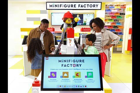 A family creating figures at the personalisation station in Lego's New York store with a sign saying 'Minifigure Factory'